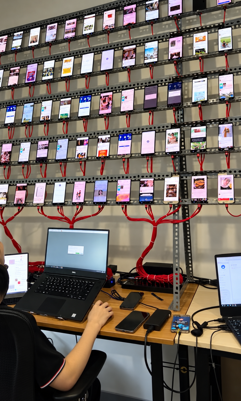 Wall-mounted phone farm with multiple connected devices and control laptops